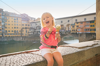 Happy baby girl eating ice cream near ponte vecchio in florence,