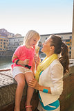 Mother and baby girl eating ice cream near ponte vecchio in flor