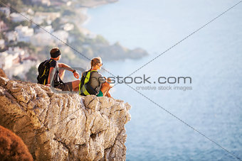 Young couple sitting on rock and enjoying beautiful view