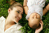 Mother With Little Baby Daughter Laying On Grass