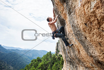 Young male rock climber on challenging route on cliff