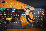 Young man practicing bouldering in indoor climbing gym