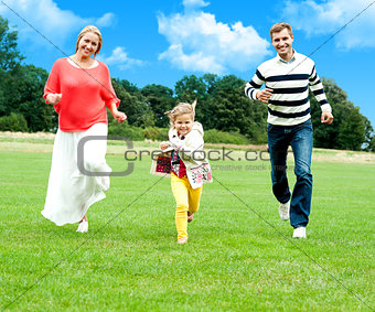 Young couple racing with their cute little daughter