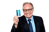 Old man wearing eyeglasses holding up a cash card