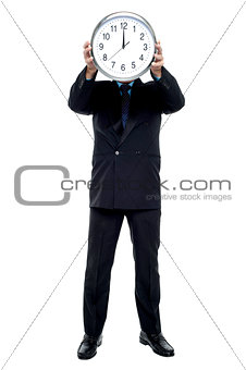 Executive holding up wall clock in front of his face