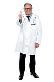 Successful senior doctor showing thumbs up sign to the camera
