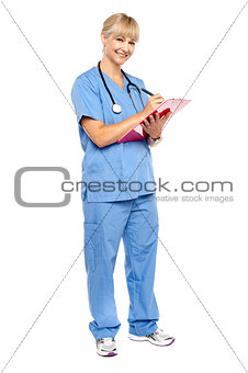Smiling nurse preparing case sheet of a patient
