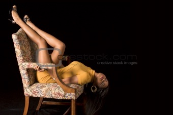 Glamorous black girl with legs high in chair (eyes closed)