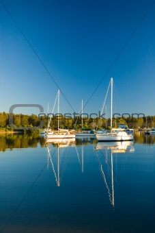 Moored yachts reflected against blue sky