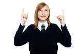 Amused schoolgirl looking and pointing upwards