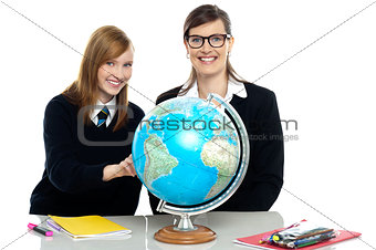 Teacher and student viewing globe in geography classroom