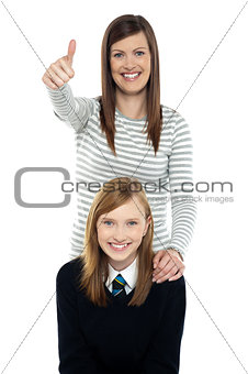 Cute schoolgirl with her mom. Mother gesturing thumbs up
