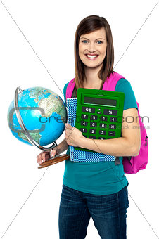Smiling female student holding a calculator and globe