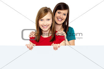 Girl holding ad board with her mother behind her