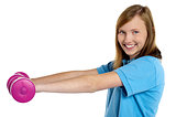 Young fit girl exercising with pink dumbbells