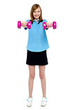 Slim girl striking a pose with dumbbells. Lifting weights