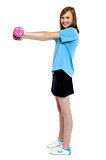Pretty teen working out with pink dumbbells