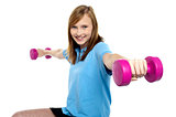 Cute young girl stretching dumbbells sideways