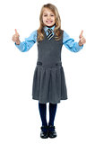 Pretty school child showing thumbs up gesture