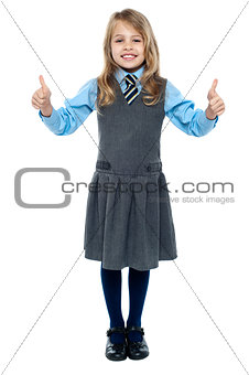 Pretty school child showing thumbs up gesture
