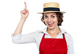 Excited chef woman pointing upwards