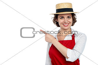 Cute woman in hat pointing sideways