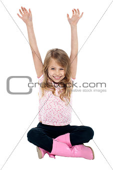 Young girl seated on floor posing with raised arms