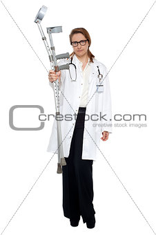 Serious faced doctor holding crutches