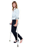 Pensive looking woman using crutches to walk