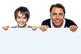 Father and son posing behind big blank banner ad