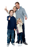 Adorable family in winter clothes gesturing thumbs up