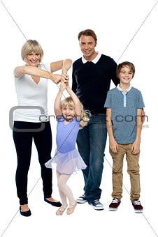 Mother helping her little ballerina twirl. Family beside
