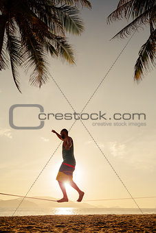teenage balancing on slackline on the beach