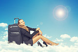 Woman sitting on clouds, leaning back in traveling bag, smiling