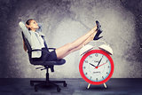 Businesswoman sits in chair. Put your feet up on big red alarm clock