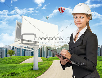 Businesswoman holding clipboard. Large billboard, road, grass hills and city as backdrop