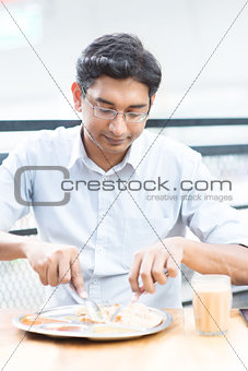 Handsome man eating food at cafeteria.