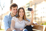 Couple photographing a selfie with a smart phone in a park