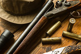 Hunting rifle, ammunition, a knife and a cap on the table