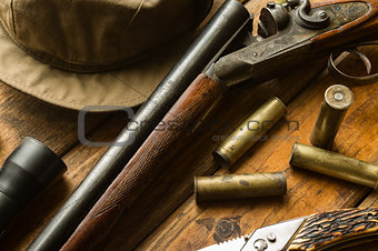 Hunting rifle, ammunition, a knife and a cap on the table