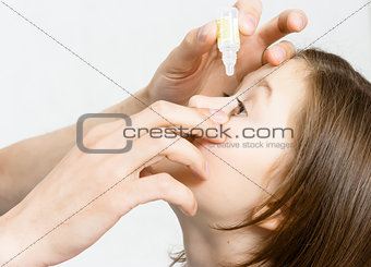 hand dripping drug solution in the eyes of a child