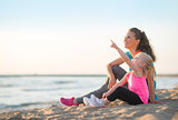 Healthy mother and baby girl pointing while sitting on beach in 
