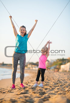 Healthy mother and baby girl rejoicing in the evening on beach