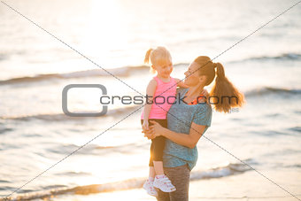 Healthy mother and baby girl on beach in the evening