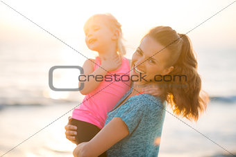 Portrait of healthy mother and baby girl on beach in the evening