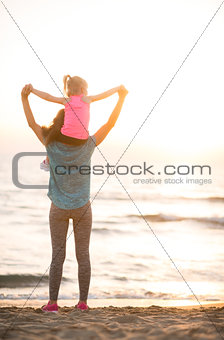 Baby girl sitting on shoulders of mother and rejoicing while on 