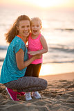 Portrait of healthy mother and baby girl on beach in the evening
