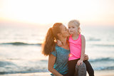 Healthy mother and baby girl kissing on beach in the evening
