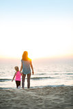 Healthy mother and baby girl walking on beach in the evening. re