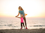 Mother and baby girl having fun time on beach in the evening